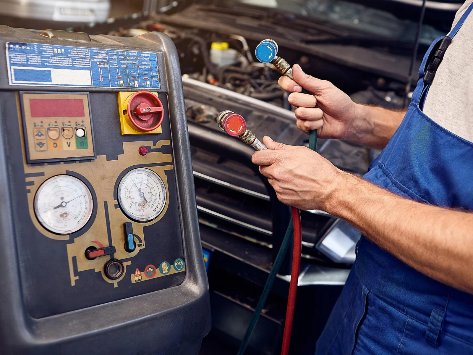 Mehaanik ühendab kliimaseadme hooldusjaama voolikuid auto külge